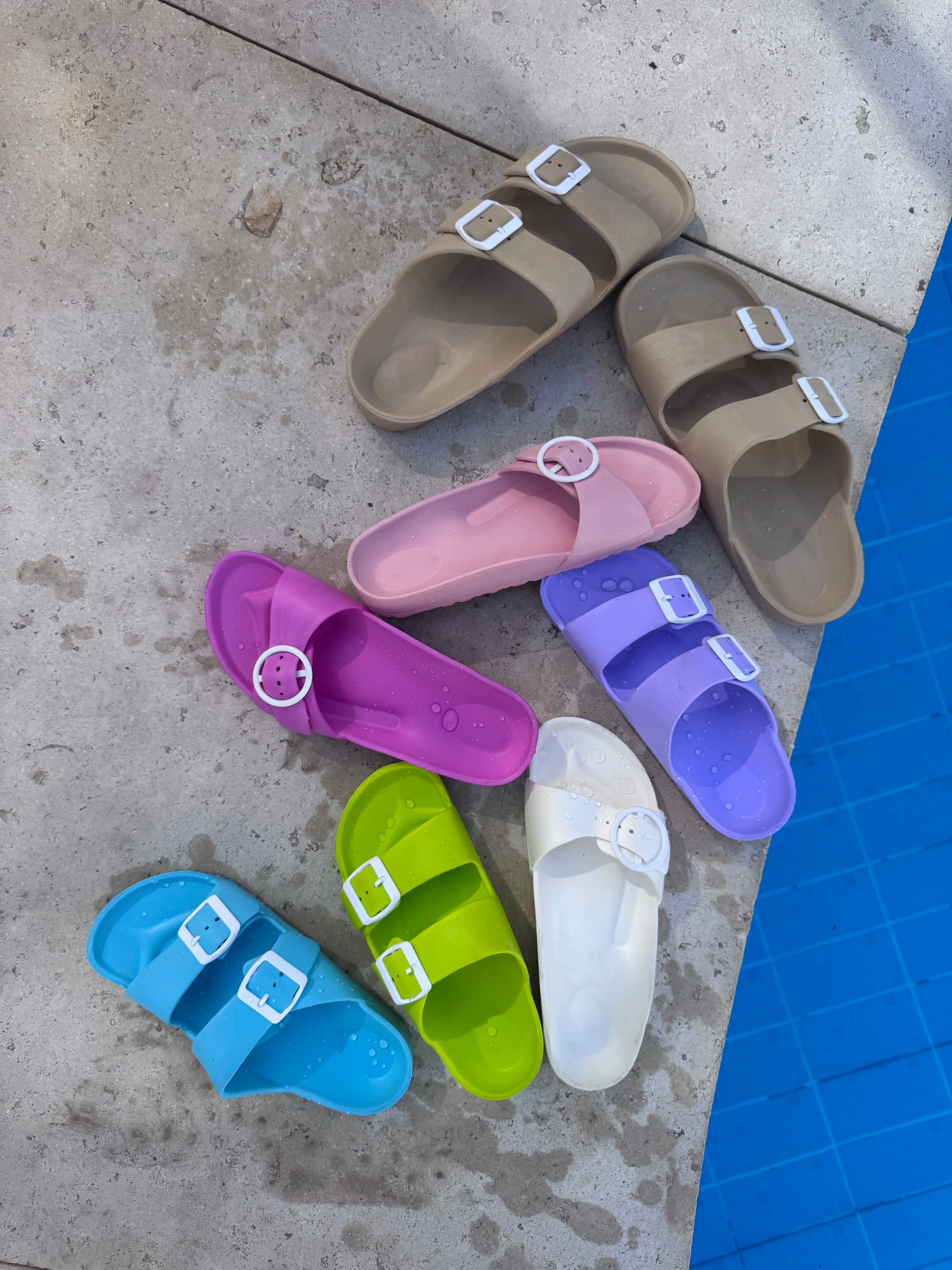 Colorful sandals on a concrete surface near a pool.
